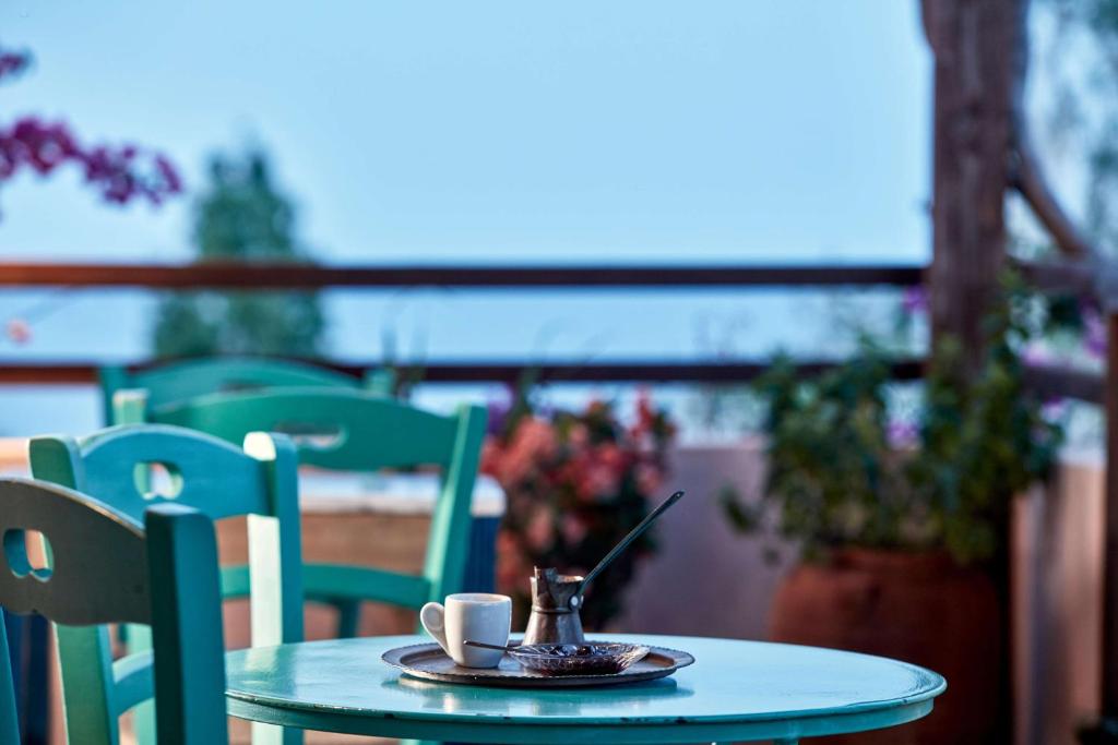 Kafijas tase un kafijas pagatavošanas katliņš uz zaļas galda, ar ziediem un ainavu fona. Ideāla vieta relaksācijai un baudīšanai.