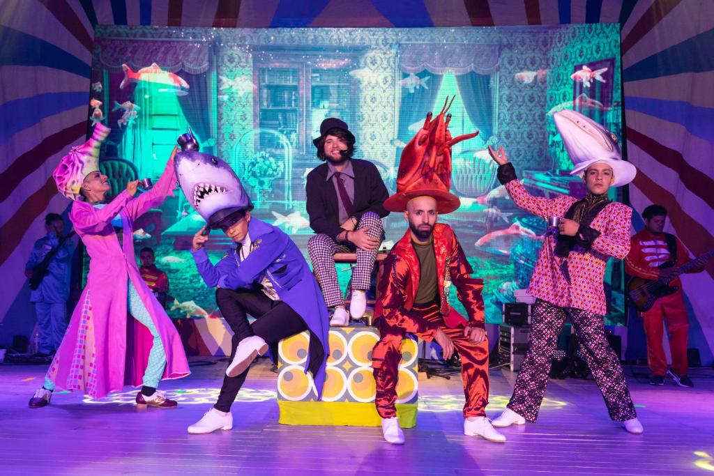 Krāsains un jautrs skatuves priekšnesums ar dejotājiem, kas valkā oriģinālus dzīvnieku kostīmus, piemēram, haizivis un garneles, uz spilgti dekorētas skatuves. Fons ar krāsainām zivīm un interjeru piešķir ainai dzīvīgumu.