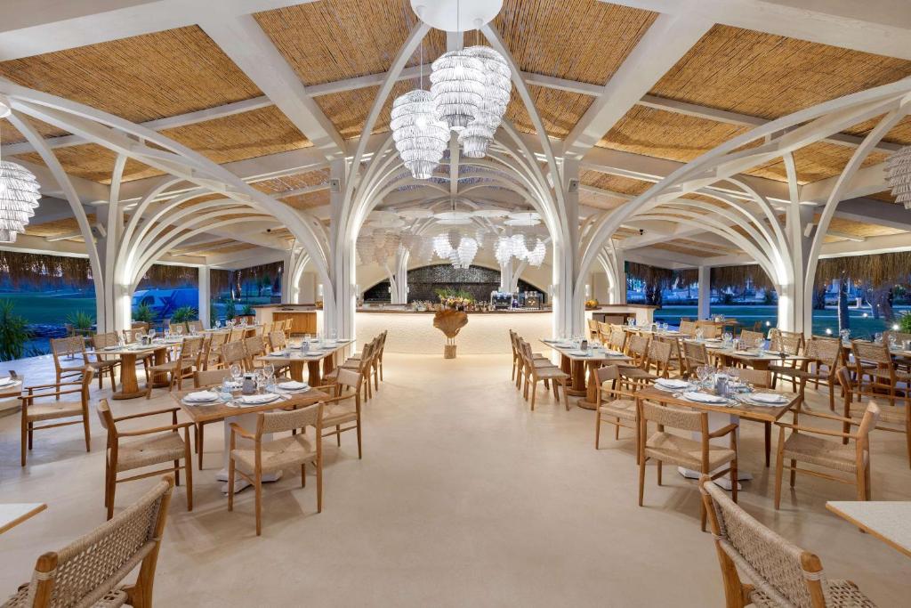 Mūsdienīgs restorāns ar elegantiem koka galdiem un krēsliem, gaišām interjera detaļām un stilīgām lampām. Skats uz dārzu un ērtu atmosfēru nodrošina patīkamu ēdināšanas pieredzi.