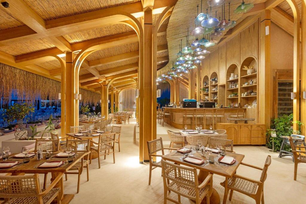 Moderns restorāns ar koka interjeru, elegantām mēbelēm un dekoratīvām gaismām, radot siltu un aicinošu atmosfēru. Ideāla vieta relaksējošai maltītei vai pasākumam.