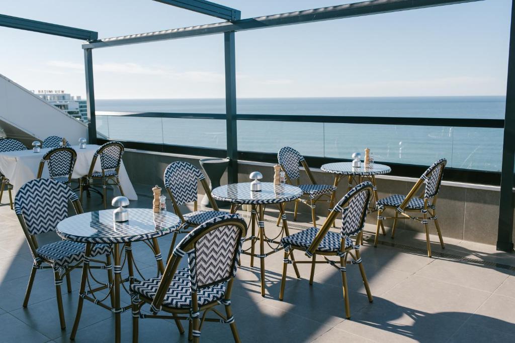 Terases restorāns ar stilīgām galdiem un krēsliem, kas piedāvā skatu uz jūru. Ideāla vieta relaksācijai un ēdienreižu baudīšanai.