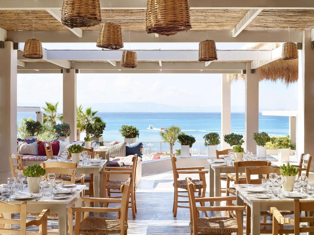 Sauļots restorāns pie jūras ar elegantiem galdiem un krēsliem, zaļajiem augiem un panaromisku skatu. Ideāla vieta relaksācijai un gastronomiskām baudām.