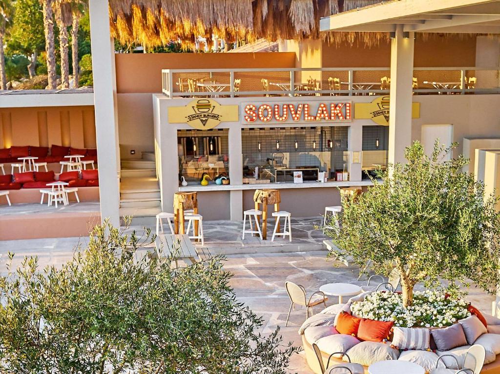 Moderns ēdināšanas punkts ar nosaukumu "Souvlaki", kas piedāvā relaksējošu atmosfēru un ērtas sēdvietas ārpus telpām, ieskauj zaļumi un dekoratīvi elementi.