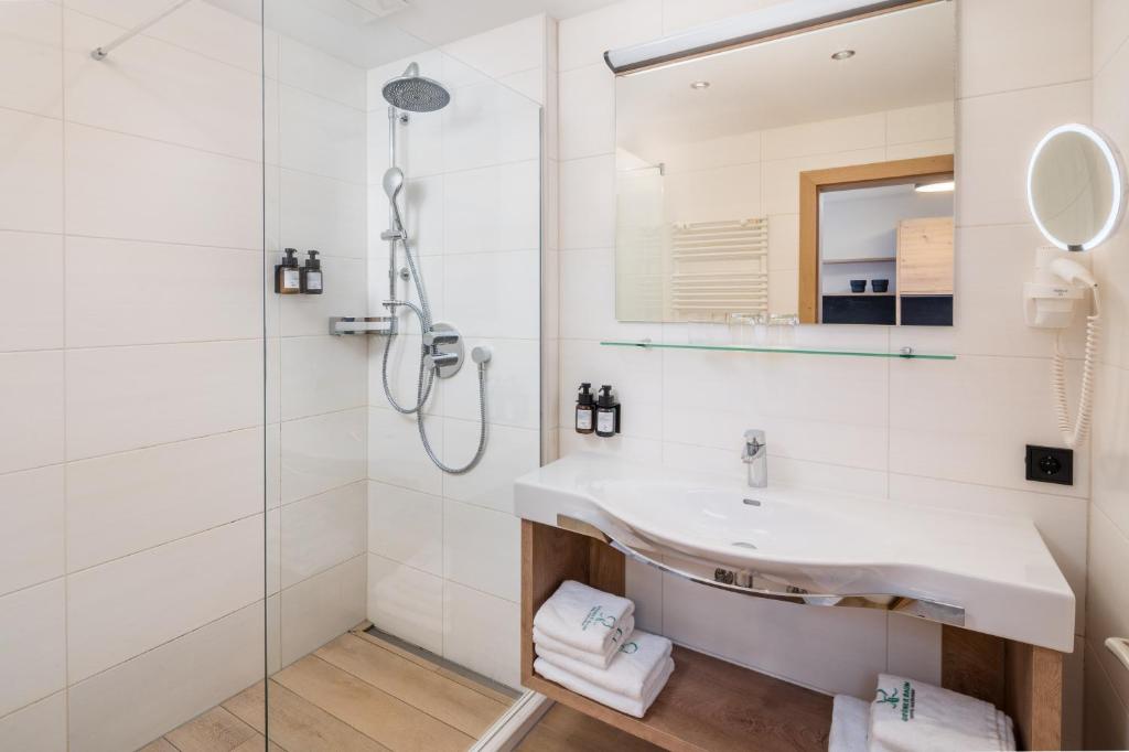 Moderns vannas istabas interjers ar dušu, spoguli un stilīgu izlietni. Svaigas dvieļi un higiēnas līdzekļi pieejami uz koka plaukta.