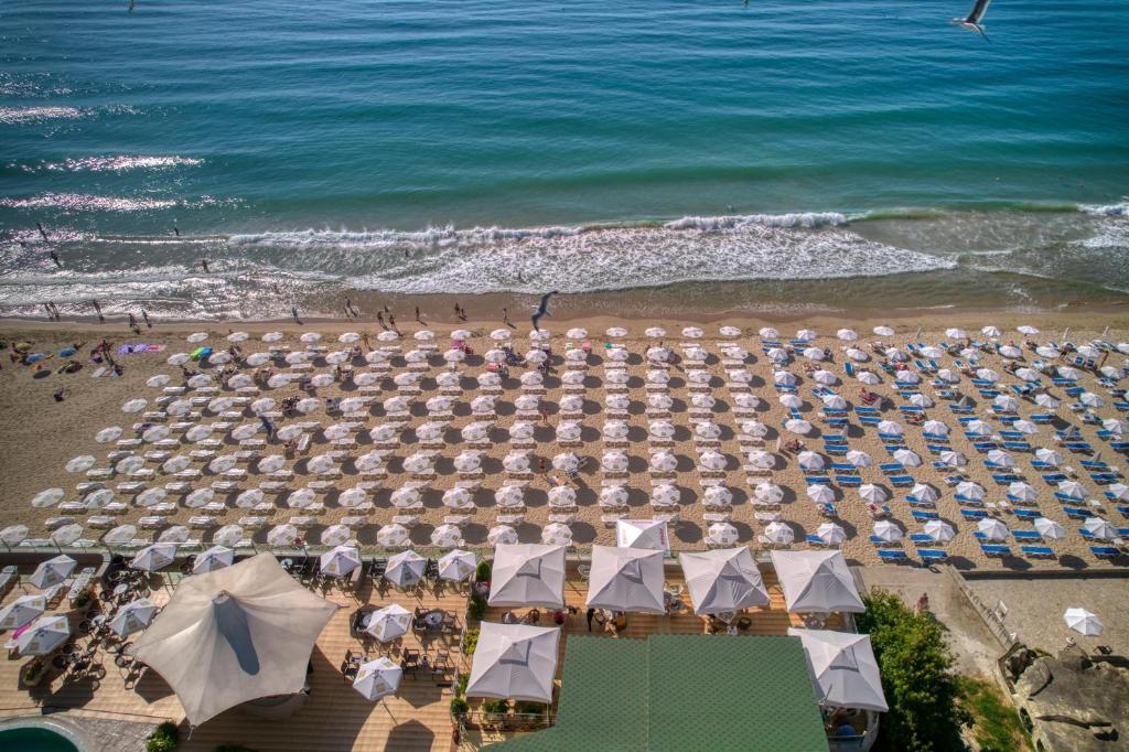 Pludmales skats ar daudziem saules aizsargiem un cilvēkiem, kas bauda jūru un sauli. Sēdošās vietas un saulessargi ir sakārtoti rindās, radot relaksējošu atmosfēru.