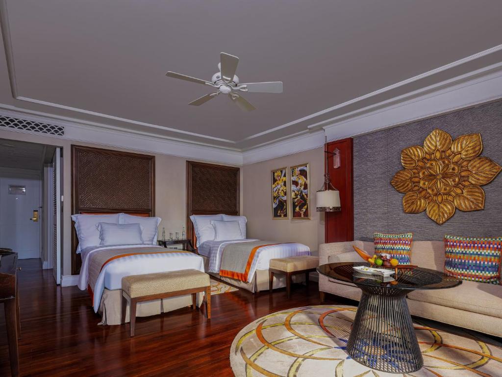 Mūsdienīgs viesnīcas numurs ar divām gultām, elegantu mēbeļu komplektu un mākslas elementiem. Telpā ir pieejams komfortabls sēžamais stūris un dekoratīvs paklājs.