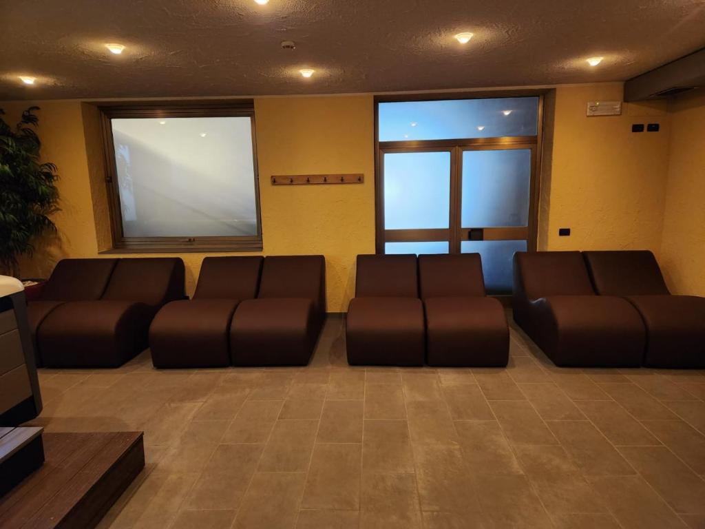 Mūsdienīgs atpūtas stūrītis ar brūniem dīvāniem, gaišām sienām un logu, kas ļauj ieplūst dabiskajai gaismai. Interjers ir vienkāršs un ērts, piemērots relaksācijai.