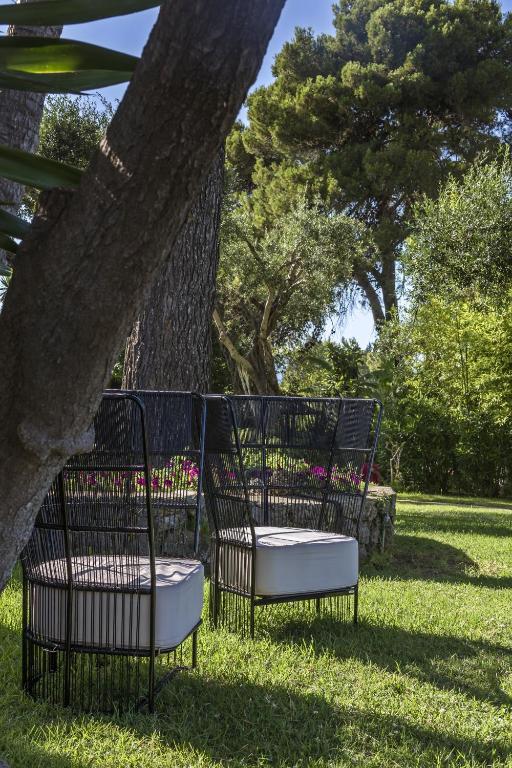 Mūsdienīga āra atpūtas zona ar melnām, stilīgām krēslām un zaļojošu dārzu fonā. Ideāla vieta relaksācijai un brīvā laika pavadīšanai.