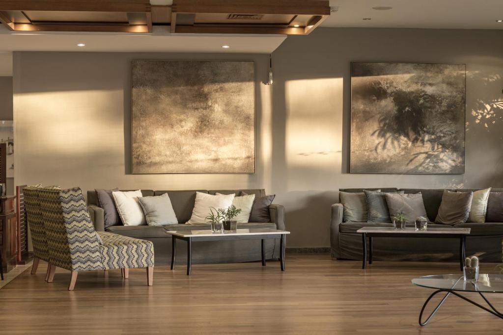 Mūsdienīgs viesnīcas interjers ar ērtām dīvānām, stilīgu galdu un mākslinieciskām gleznām uz sienām, kas rada siltu un aicinošu atmosfēru.