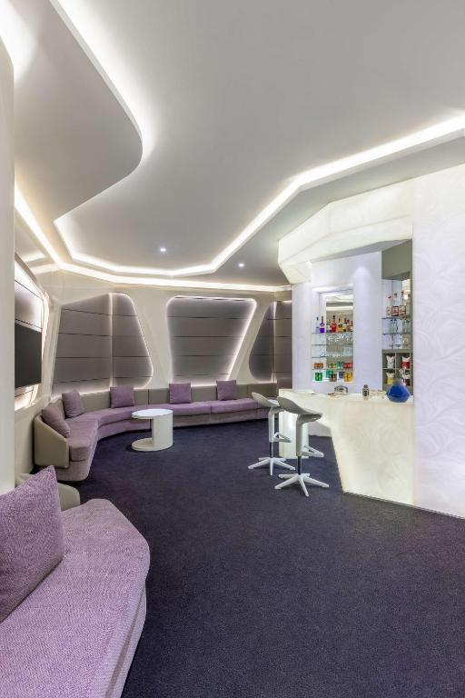 Mūsdienīgs un stilīgs interjers ar ērtām rozā dīvānu vietām un elegantu bāru, kas apgaismots ar mīkstām gaismām. Ideāla telpa relaksācijai un sociālām aktivitātēm.