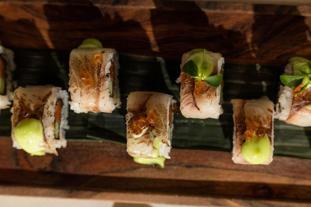 Svaigu sushi rullīši ar zivs fileju, wasabi un garnelēm, pasniegti uz banānu lapas. Ideāli piemēroti gastronomiskām baudījumiem.