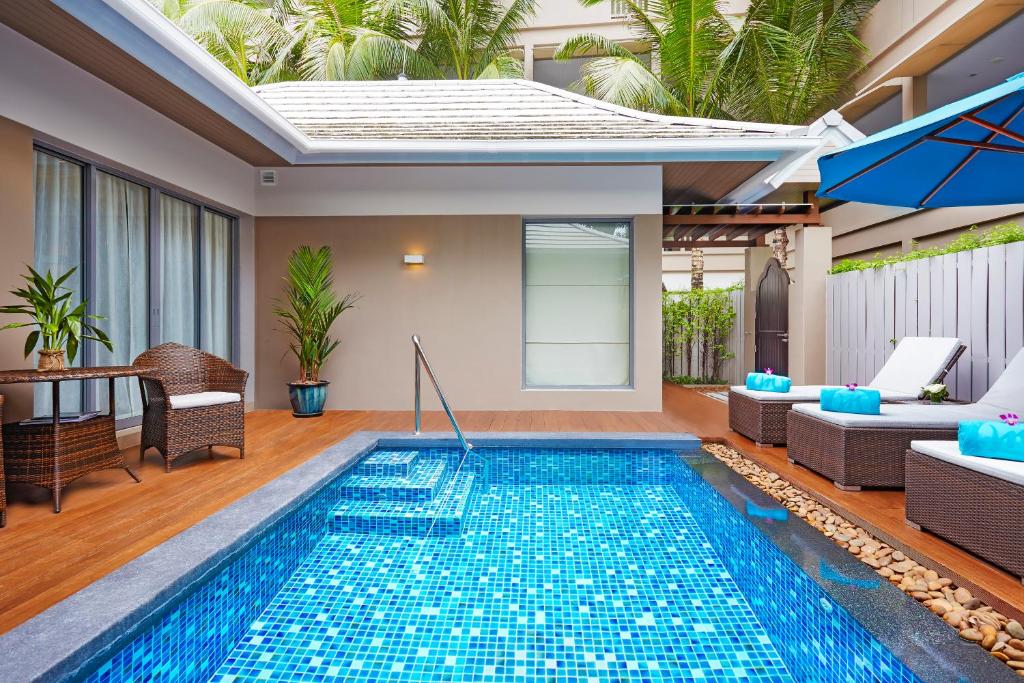 Privātais baseins Grand Mercure Phuket Patong ar sēdvietām un zaļumiem apkārt.