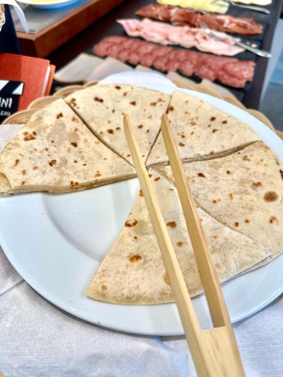 Plāksnīte ar sagrieztiem tortilju gabaliem un koka nūjiņām. Fons ir smalki gaļas šķēlītes.