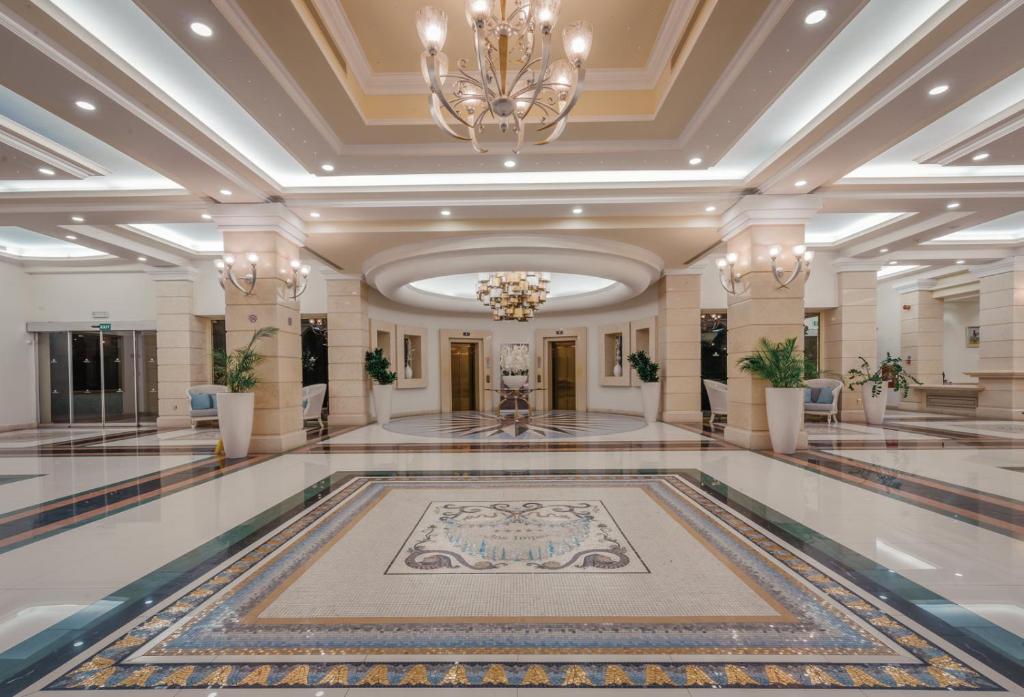 Elegants viesnīcas vestibilis ar greznu griestu apgaismojumu un dekoratīvām flīzēm. Interjers ir mūsdienīgs un izsmalcināts, radot viesmīlīgu atmosfēru.