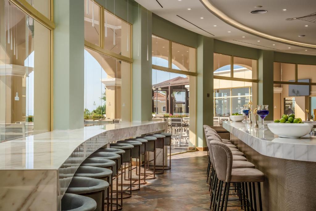 Mūsdienīgs bārs ar elegantu marmora letes dizainu un skatu uz āra terasi. Telpa ir piepildīta ar gaismu, radot patīkamu atmosfēru.