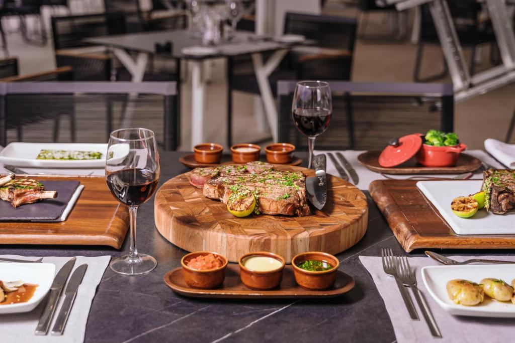 Eleganta galda klāšana ar izsmalcinātu gaļas ēdienu, sarkanvīnu un dažādiem garnējumiem. Ideāla atmosfēra gastronomiskai pieredzei.