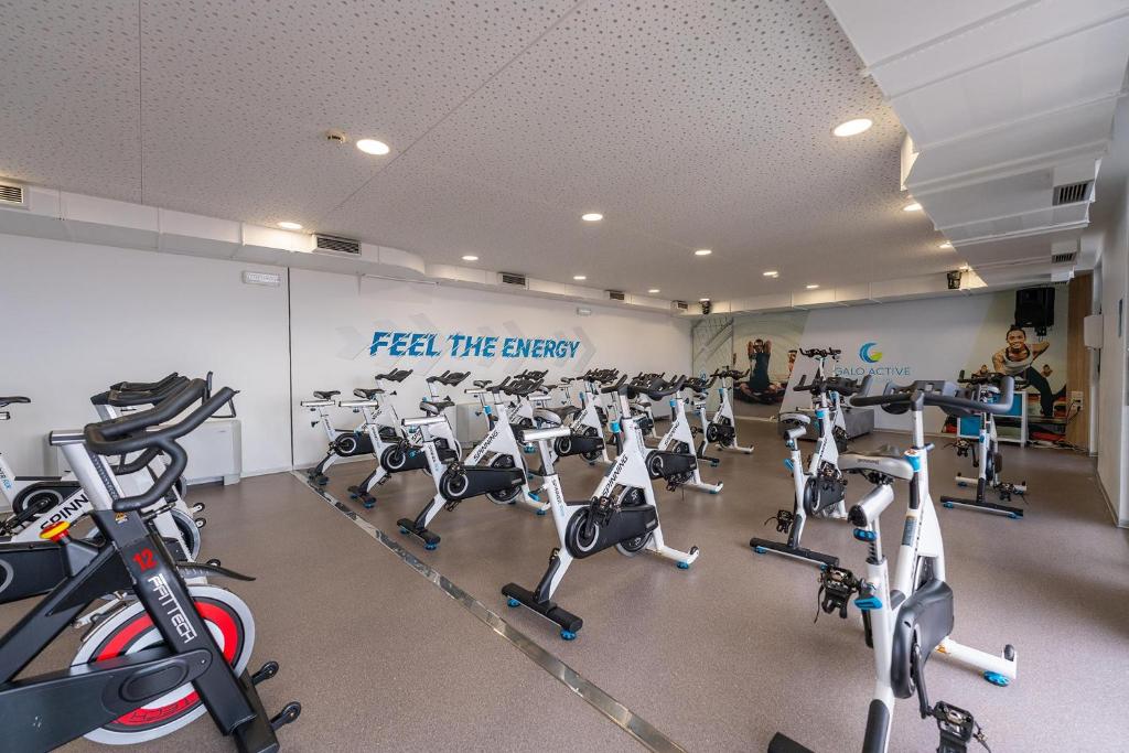 Mūsdienīga sporta zāle ar daudzām velotrenažieriem un motivējošu sienu ar uzrakstu 