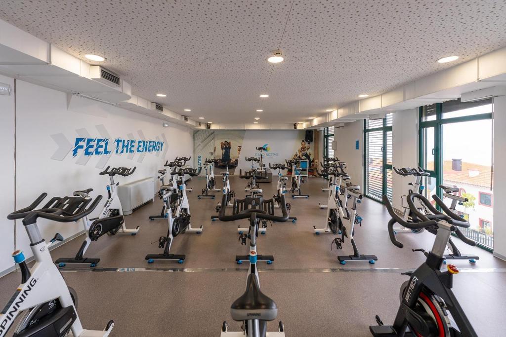 Velotrenēšanas zāle ar vairākiem velosipēdiem un motivējošu sienas uzrakstu 