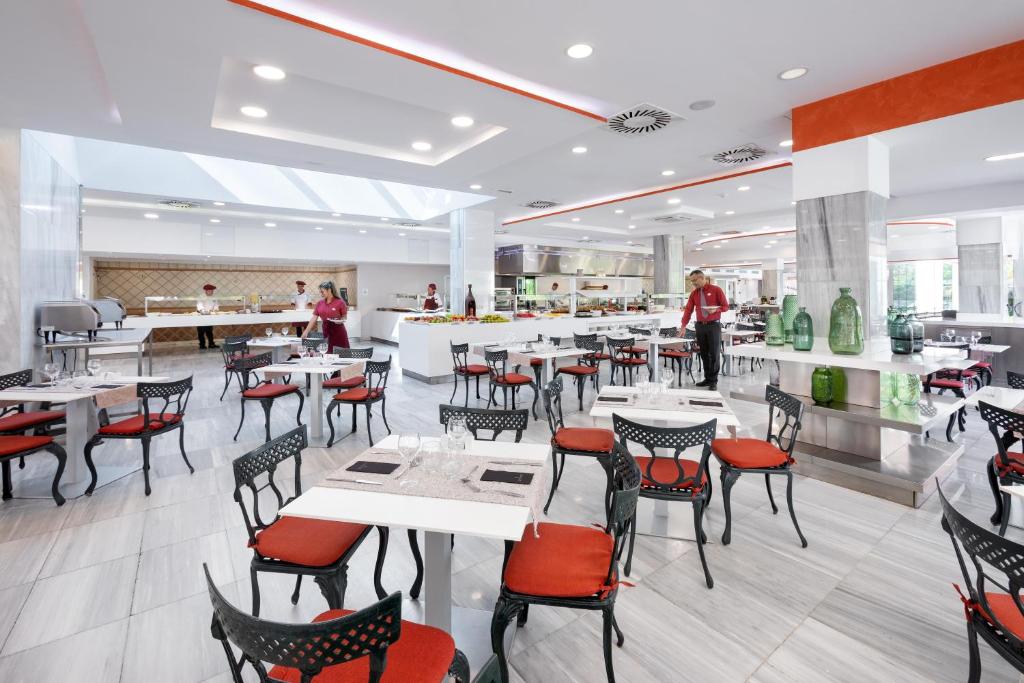 Mūsdienīgs restorāns ar elegantiem galdiem un krēsliem, kas piedāvā plašu ēdienu izvēli un patīkamu atmosfēru. Gaismas un interjera elementi rada siltu un aicinošu vidi.