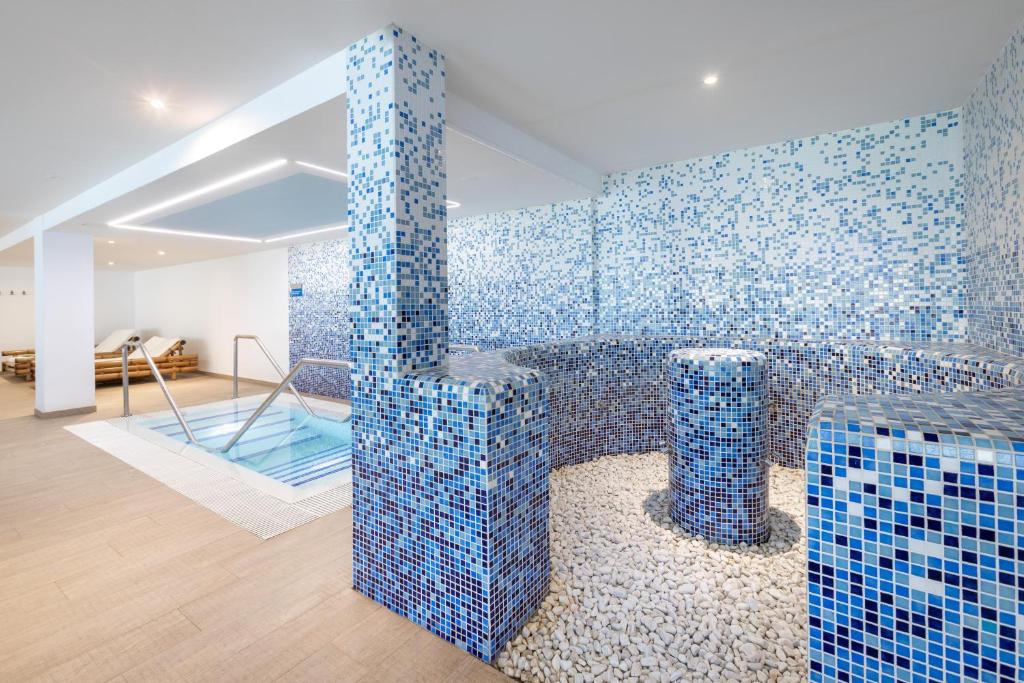 Mūsdienīgs spa ar zilām mozaīkām, relaksācijas baseinu un akmeņiem, radot mierīgu atmosfēru. Ideāla vieta atpūtai un labsajūtai.