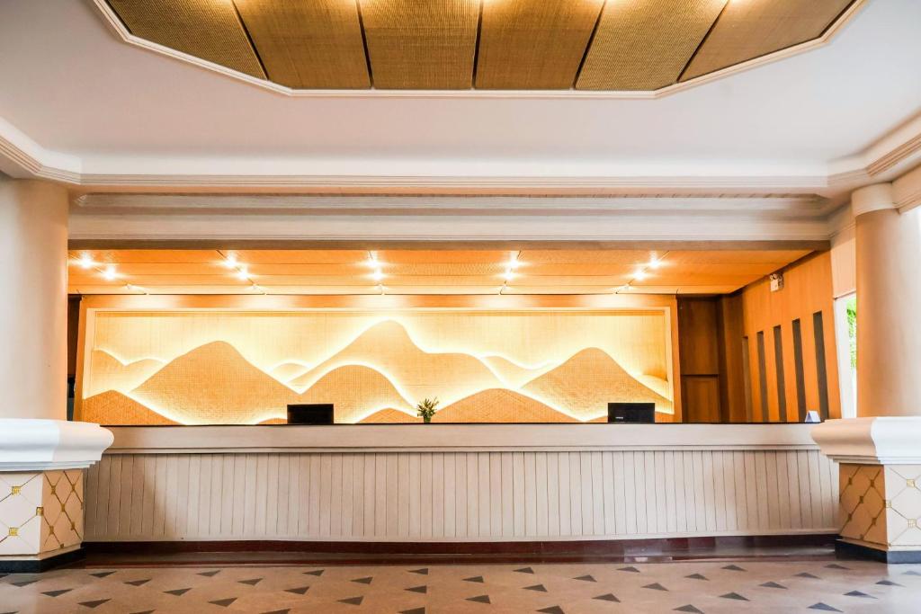 Mūsdienīga viesnīcas reģistratūra ar elegantām gaismas un kalnu formas dizaina elementiem, kas rada siltu un viesmīlīgu atmosfēru.