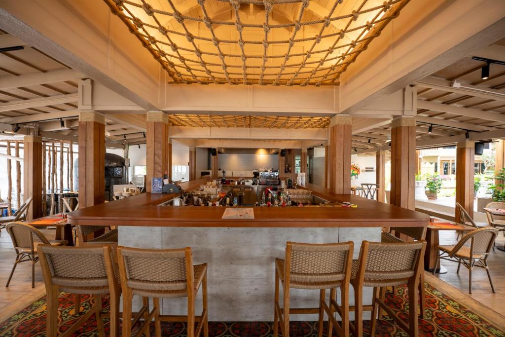 Mūsdienīgs bārs ar koka elementi un modernu interjeru, kas piedāvā ērtas sēdvietas un plašu dzērienu izvēli. Telpa ir gaiša un atvērta, radot patīkamu atmosfēru.