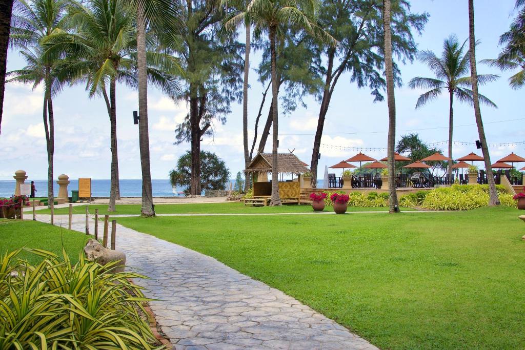 Skaista pludmales ainava ar palmām, zālienu un koka paviljonu, kas atrodas blakus jūrai. Ideāla vieta relaksācijai un atpūtai.