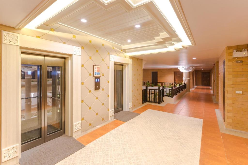 Mūsdienīgs viesnīcas gaiteņš ar divām liftu durvīm un dekoratīvu apgaismojumu. Interjers ir elegants, ar stilīgu apdari un krāsainām flīzēm.