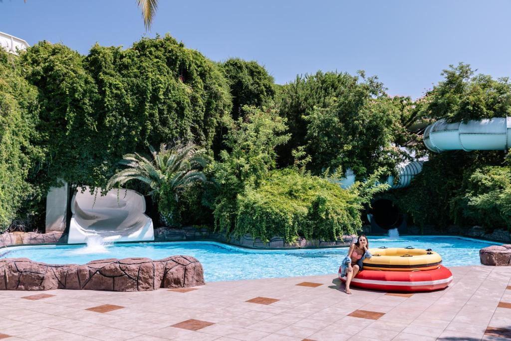 Viesnīcas Ali Bey Club peldbaseins ar ūdens slidkalniņu un palmu ainavu