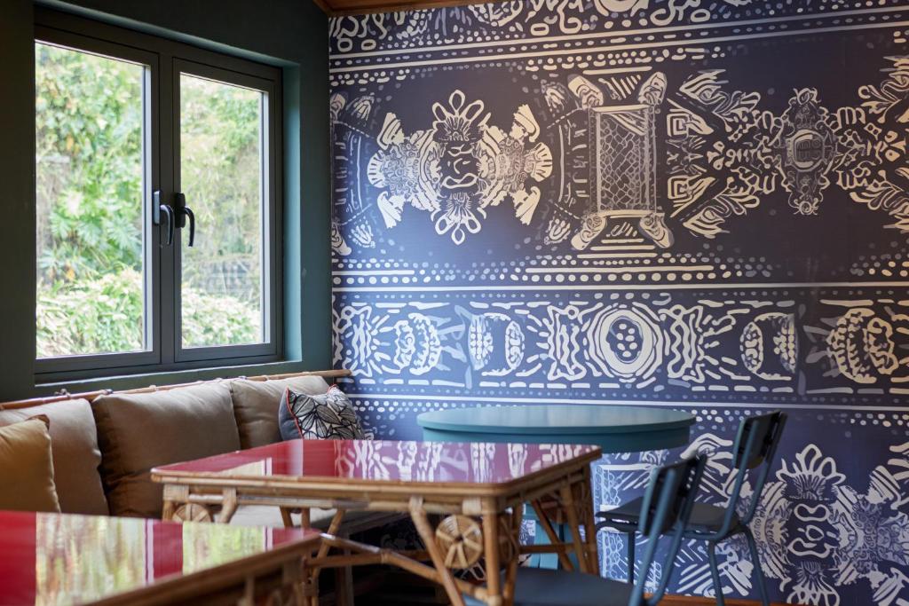 Mūsdienīgs interjers ar māksliniecisku sienu apdari un ērtu sēdvietu, kas rada patīkamu atmosfēru. Redzama liela loga gaisma un krāsaini galdi.