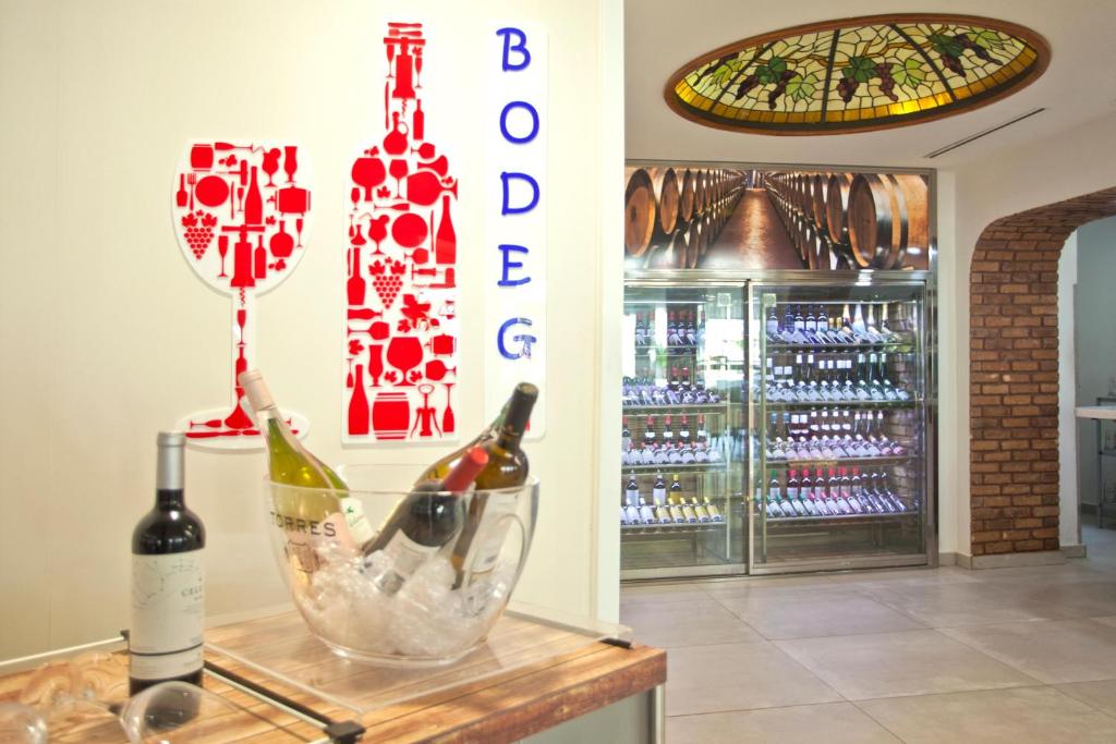 Bodegas stils interjers ar vīna pudelēm un glāzēm, kā arī vitrīnu ar dažādiem vīniem. Stikla griestu dizains ar vīnogām piešķir telpai unikālu atmosfēru.