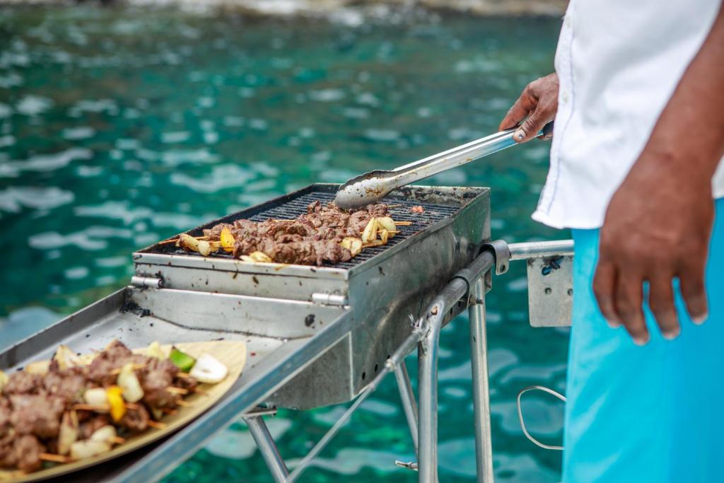 Grilēšana pie ūdens, kur tiek pagatavota gaļa un dārzeņi. Šis ēdiens ir pasniegts uz šķīvja blakus grilam.