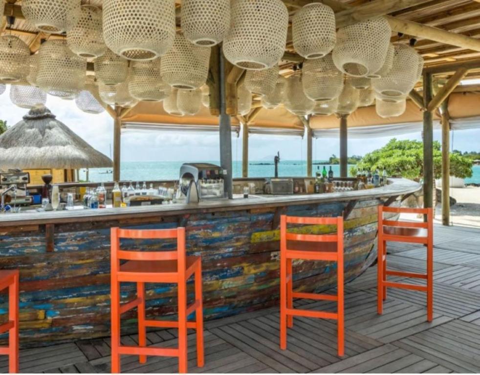 Tropu bārs ar krāsainiem augstajiem krēsliem un rotājošām lampām, kas piedāvā skatu uz jūru. Ideāla vieta atpūtai un relaksācijai.