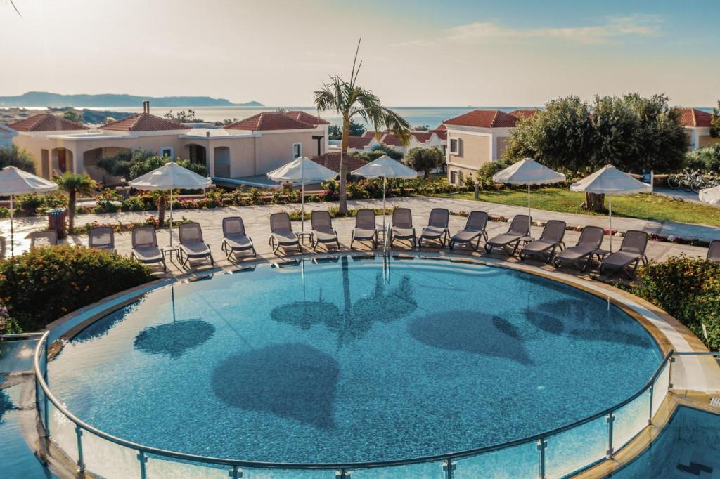 Luksusa viesnīcas baseins ar sauļošanās krēsliem un baltiem saulessargiem, skaista ainava ar jūru fona. Ideāla vieta relaksācijai un atpūtai.
