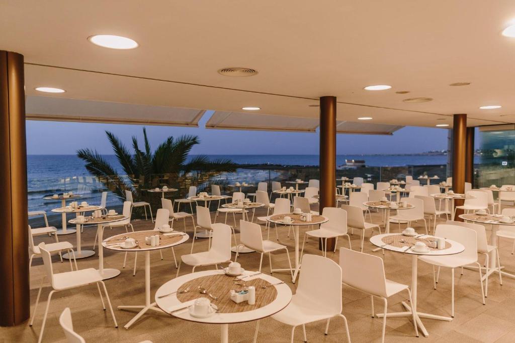 Mūsdienīgs restorāns ar baltām mēbelēm un jūras skatu, kas ir ideāls vietas izvēle brokastīm vai vakariņām. Interjers ir gaišs un plašs, radot relaksējošu atmosfēru.