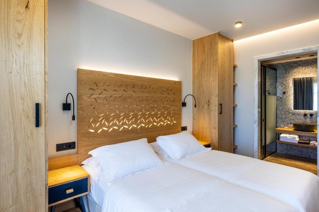 Mūsdienīgs guļamistabas interjers ar koka gultas galvgali, kas rotāts ar ģeometriskiem rakstiem, un stilīgu vannas istabu. Telpā ir gaiša krāsa un eleganta apgaismojuma sistēma.