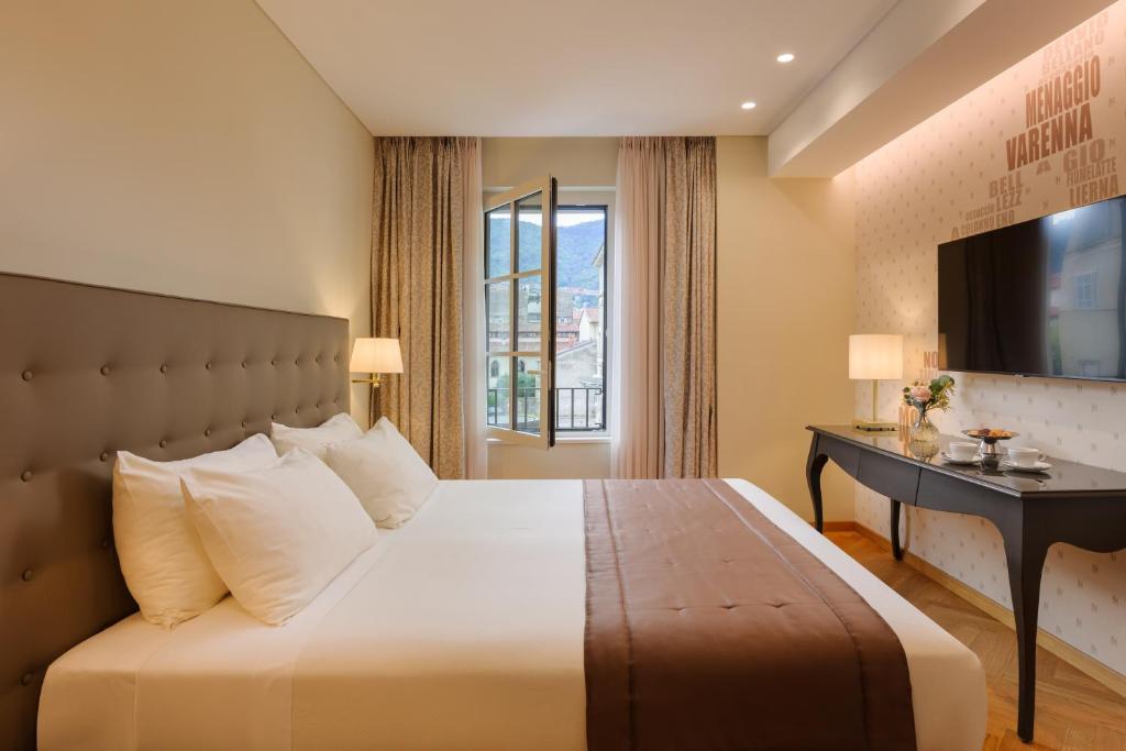 Moderns viesnīcas numurs ar ērtu gultu, elegantiem aksesuāriem un logu, kas paver skatu uz apkārtni. Gaismota telpa ar televizoru un galdu, kas paredzēts relaksācijai.