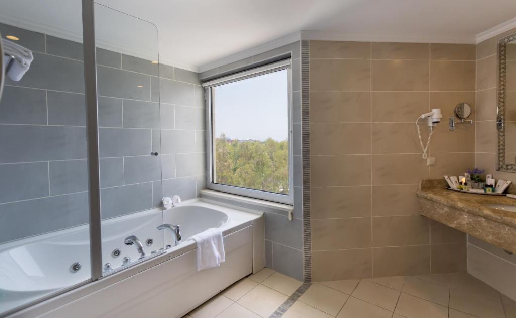 Mūsdienīgs vannas istabas interjers ar masāžas vannu, lieliem logiem un elegantiem akmens izstrādājumiem. Dabiska gaisma un skaista ainava nodrošina relaksējošu atmosfēru.