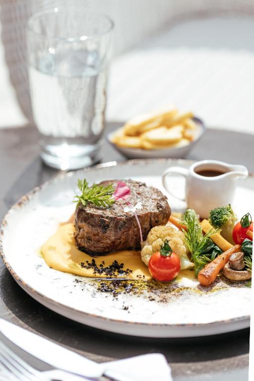 Svaiga gaļas šķēle ar dārzeņiem un kartupeļiem, pasniegta ar mērci un ūdeni. Ideāla maltīte gourmet restorānam.