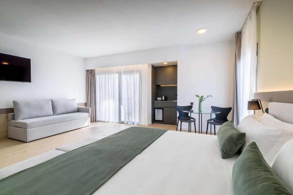 Mūsdienīgs viesnīcas numurs ar ērtu dīvānu, televizoru un nelielu virtuvi. Telpa ir gaiša un plaša, ar piekļuvi balkoniem un modernām mēbelēm.