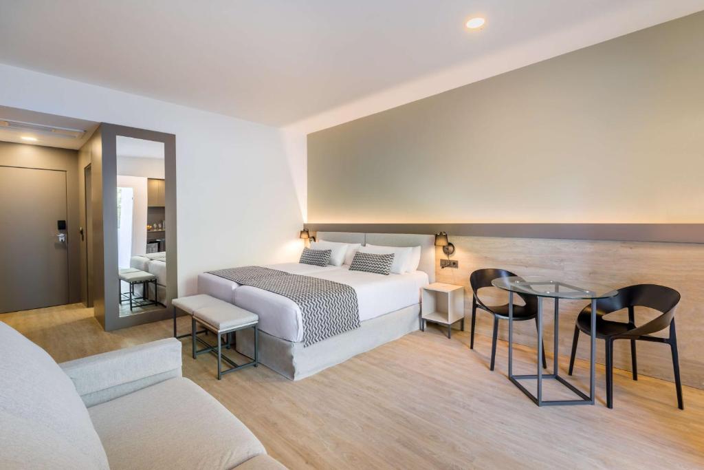 Mūsdienīgs viesnīcas numurs ar lielu gultu, ērtu dīvānu un galdu, kas paredzēts relaksācijai. Interjers ir gaišs un elegants, radot patīkamu atmosfēru.