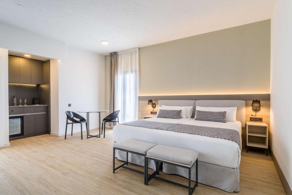 Mūsdienīga viesnīcas numura iekārtojums ar gultu, ērtu sēdvietu un mini virtuvi. Gaismas un neitrālas krāsas rada relaksējošu atmosfēru.