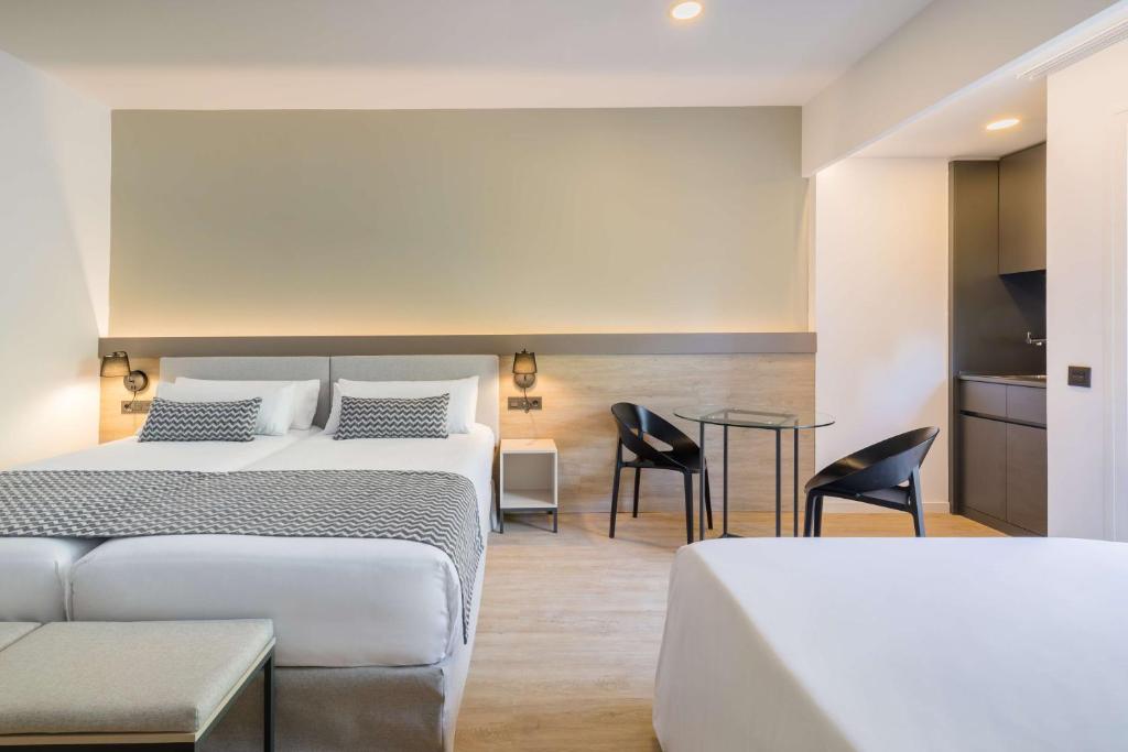 Moderns viesnīcas numurs ar divām gultām, stikla galdu un krēsliem, kā arī mini virtuvi. Gaismas un neitrālas krāsas radījušas mājīgu atmosfēru.