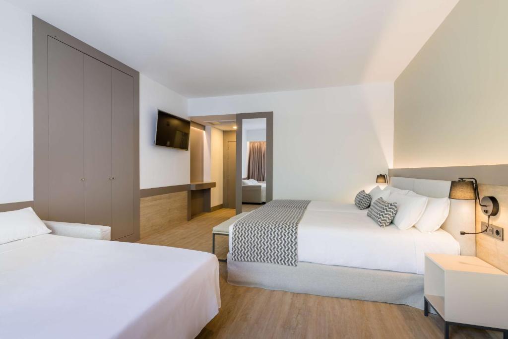 Mūsdienīga viesnīcas istaba ar divām gultām, televizoru un ērtu interjeru. Gaismas toņi un funkcionāls dizains veido relaksējošu atmosfēru.