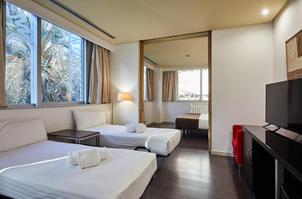 Mūsdienīga viesnīcas numura interjers ar divām atsevišķām gultām, televizoru un logiem, caur kuriem redzams zaļš ainavas elements. Ideāli piemērots ērtai atpūtai.