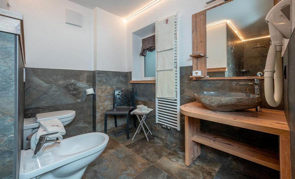 Moderns vannas istabas interjers ar akmens izskata flīzēm, koka izlietni un mūsdienīgu sanitāro tehniku. Telpa ir gaiša un eleganta, ar minimālistisku dizainu.