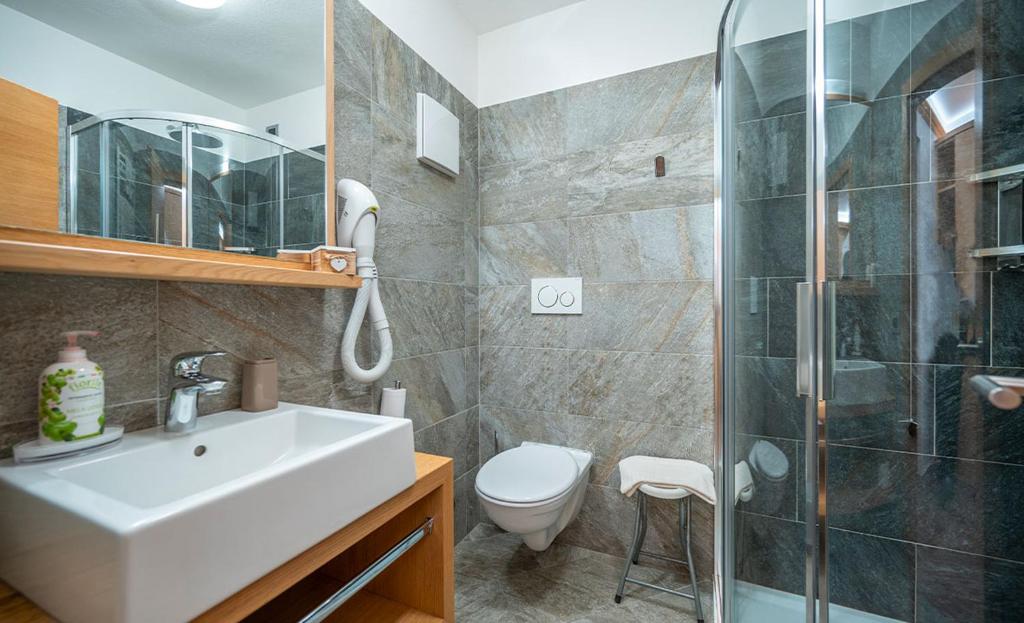 Moderns vannas istabas interjers ar akmens apdari, stikla dušu un koka elementiem. Šī telpa piedāvā elegantu un funkcionālu dizainu.