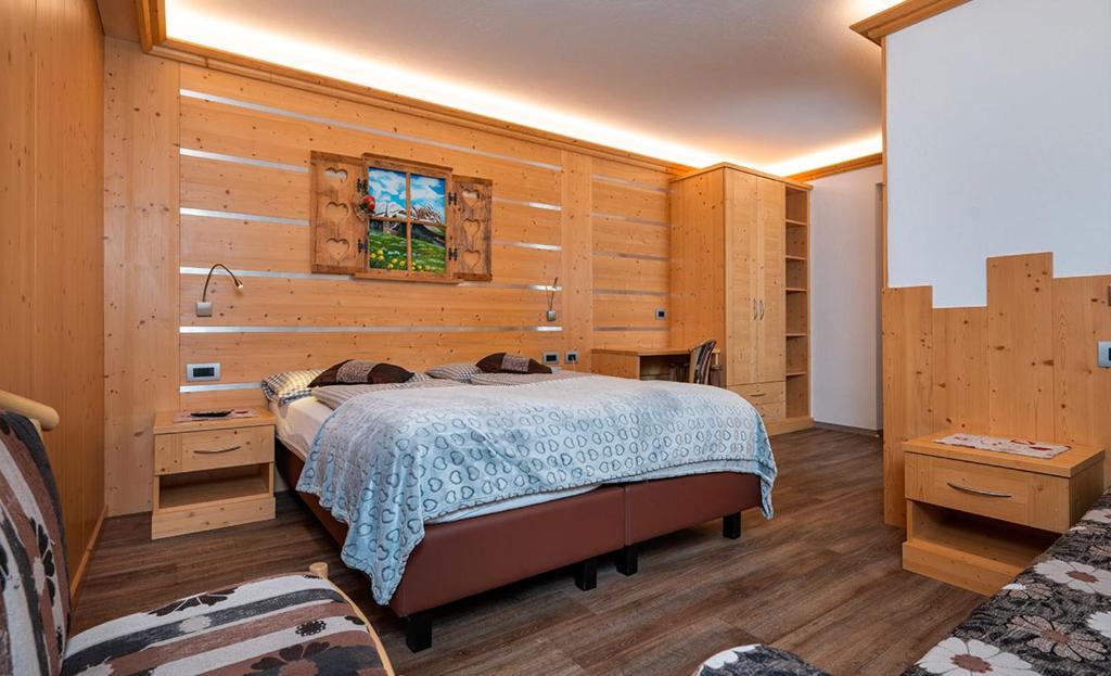 Mūsdienīgs guļamistabas interjers ar koka apdari, ērtiem gultas veļas elementiem un mākslas darbu uz sienas. Telpa ir gaiša un viesmīlīga, radot patīkamu atmosfēru.