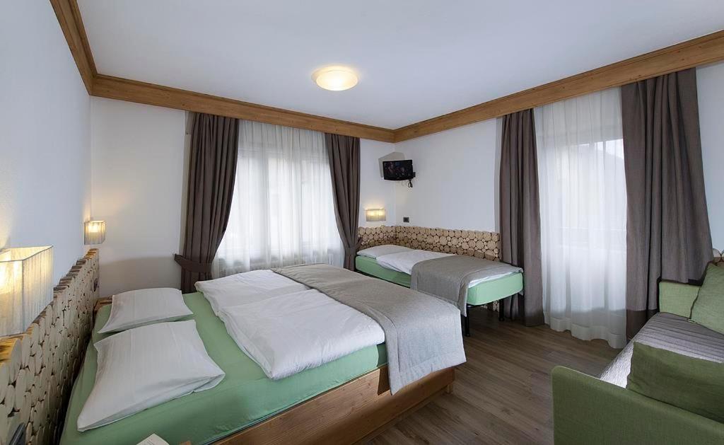 Mūsdienīgs viesnīcas numurs ar divām gultām un dīvānu, papildināts ar koka elementiem un dabīgu apgaismojumu. Numurā ir liels logs, kas nodrošina gaišu un ērtu atmosfēru.