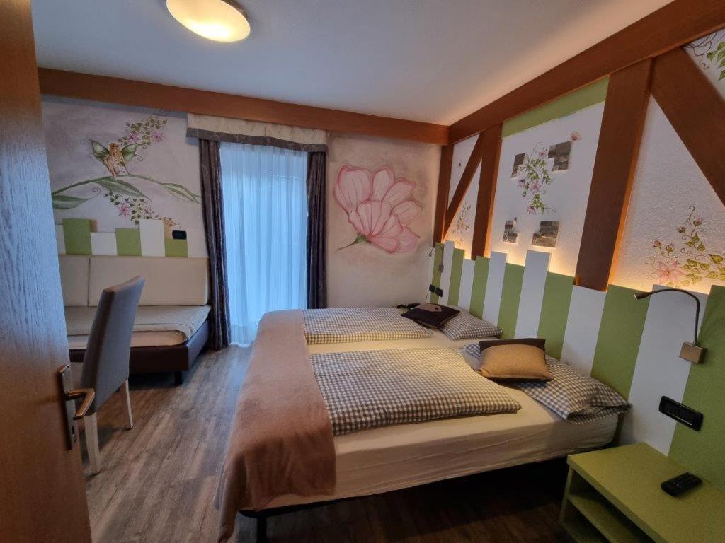 Mūsdienīga viesnīcas numura iekšskats ar divām gultām, modernu interjeru un krāsainām sienu gleznām, kas rada patīkamu un relaksējošu atmosfēru.